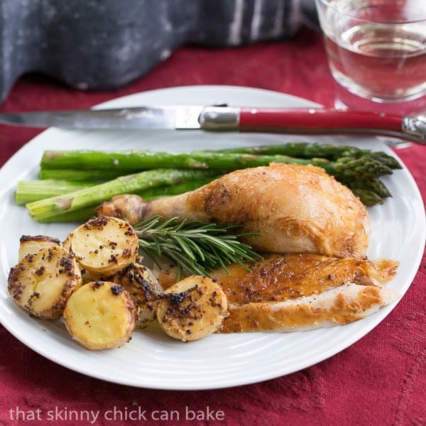 Classic Roast Chicken with Mustard Potatoes on a white dinner plate.