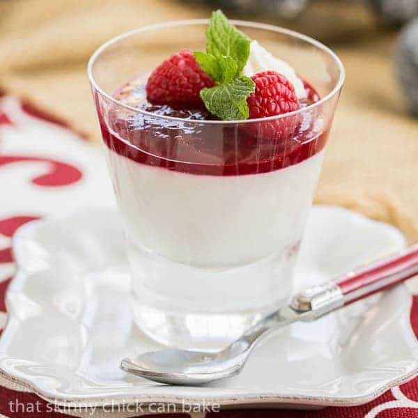Raspberry White Chocolate Cheesecake Parfaits in a glass on a white plate.