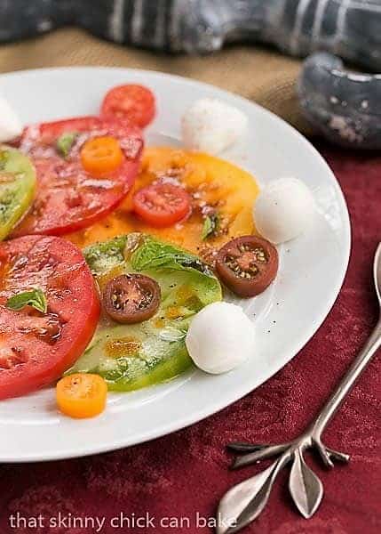 Salade de Tomates et Fromage - a simple French salad of juicy ripe tomatoes, fresh mozzarella and basil Salade de Tomates et Fromage on a white ceramic plate