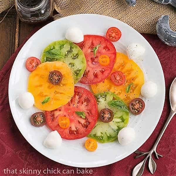 Salade de Tomates et Fromage - a simple French salad of juicy ripe tomatoes, fresh mozzarella and basil Salade de Tomates et Fromage on a white ceramic plate