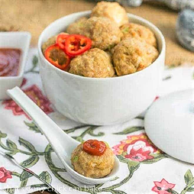 Sesame Ginger Meatballs in a white ceramic bowl with one topped with sriracha in a white ceramic spoon.