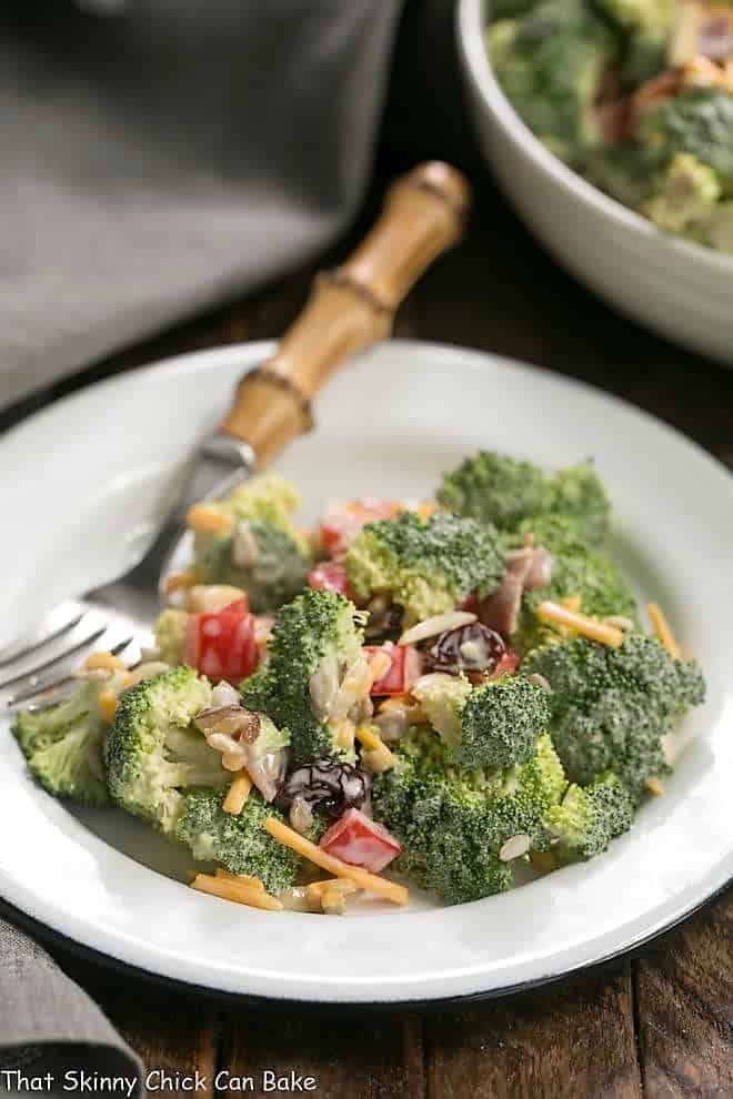 Broccoli Salad with Bacon and Dried Cherries - Perfect for picnics and potlucks! Broccoli Salad with Bacon and Dried Cherries on a white plate with a bamboo handled fork.