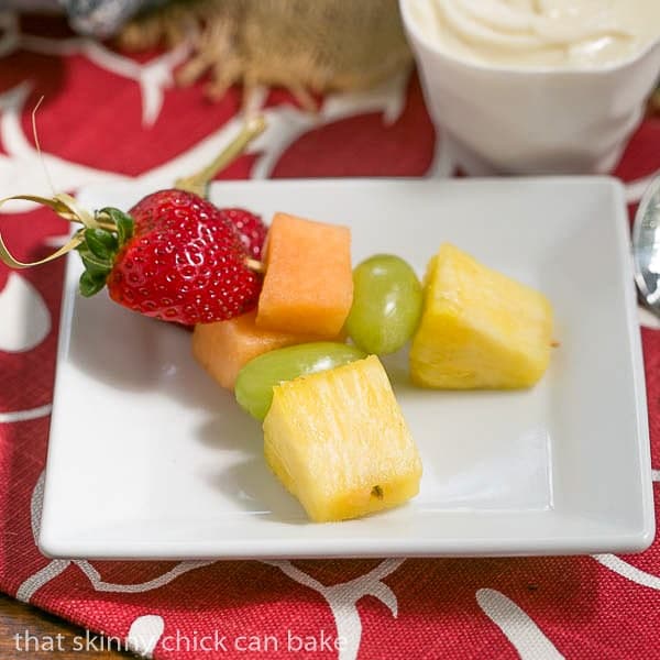 Two Fruit Kebabs with White Chocolate Mascarpone Dip on a square white plate.
