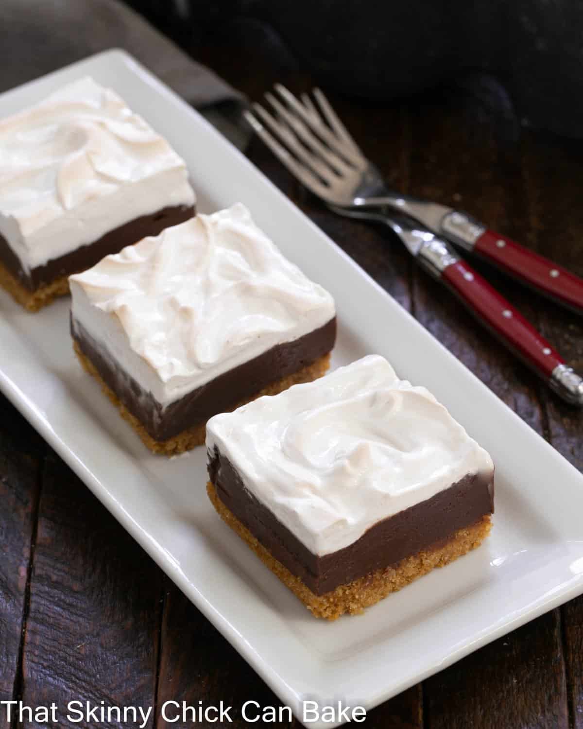 3 S'mores bars on a white ceramic tray with 2 forks.