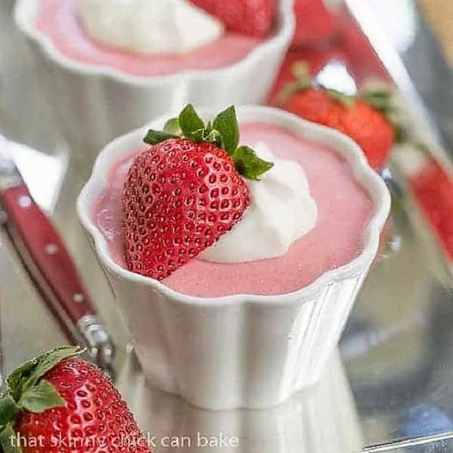 Strawberry Mousse - A sweet. creamy spring time berry dessert Strawberry Mousse in small white ramekins garnished with whipped cream and half a strawberry.