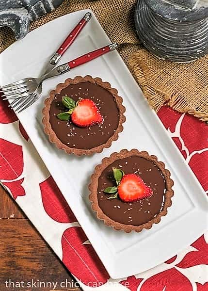 Recipe for Individual Chocolate Tarts - An elegant chocolate dessert Two Double Chocolate Tartlets on a white rectangular platter with two red handled forks