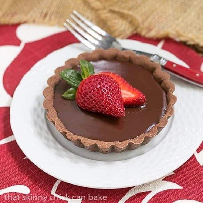Double Chocolate Tartlets - An elegant chocolate dessert Double Chocolate Tartlet toped with a strawberry on a white plate