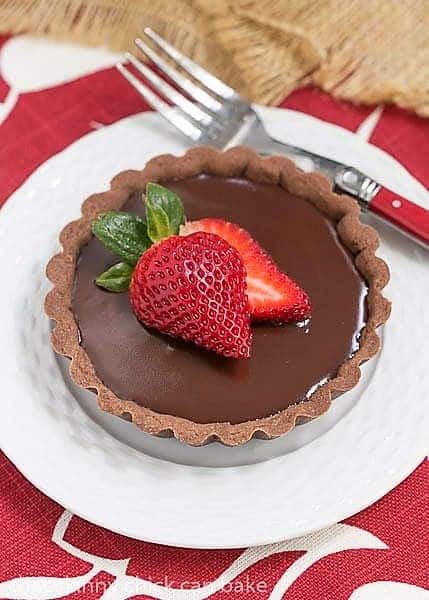 Chocolate Ganache Tarts - An elegant chocolate dessert A Double Chocolate Tartlets on a white dessert plate with a red handled fork