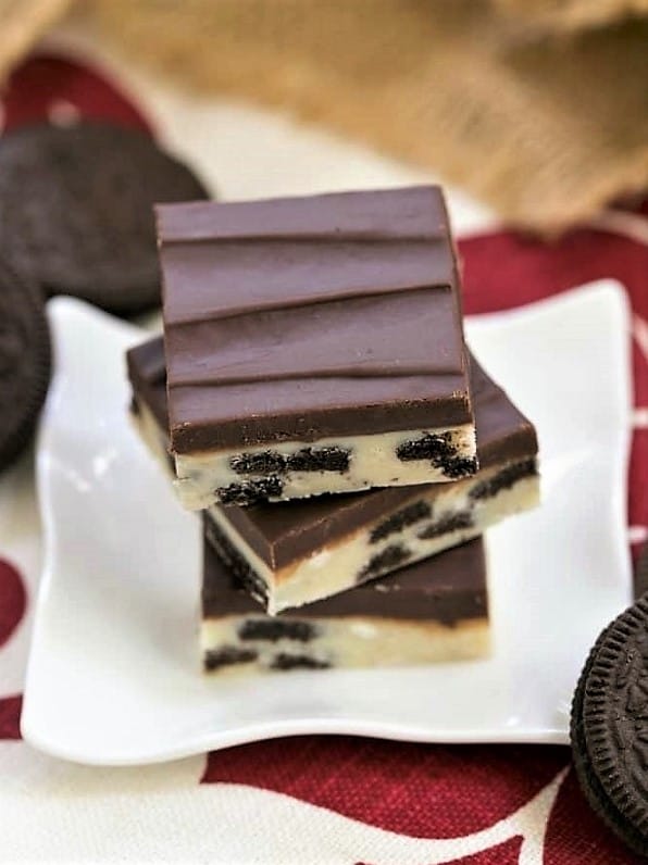 Oreo Double Decker Fudge stacked on a small white ceramic plate surrounded by Oreos