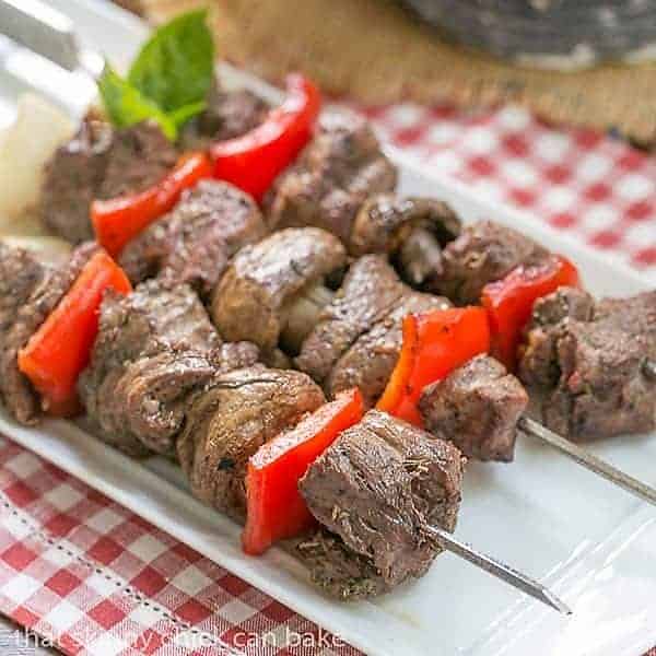 Tender Grilled Beef Steak Kabobs with a simple, flavor packed marinade on skewers and resting on a white platter. Tender Skewered Grilled Beef Steak Kabobs on a white tray.