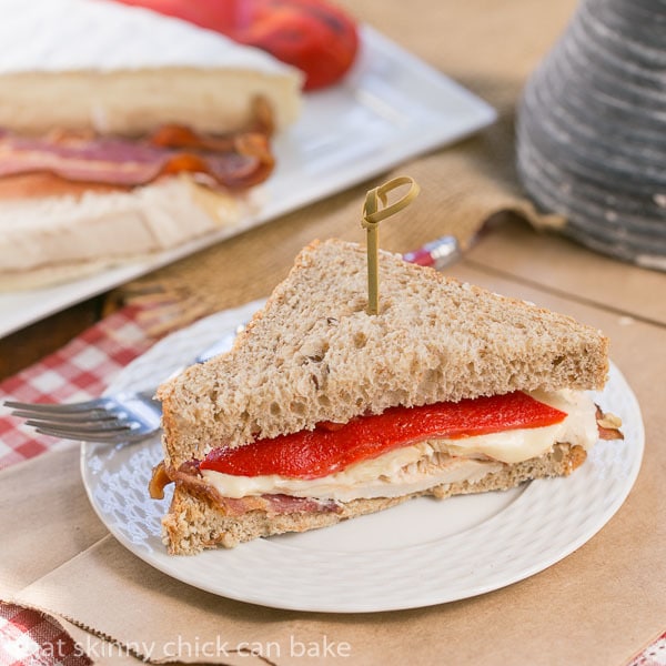 Half of a Roasted Chicken Brie and Bacon Sandwich on a white luncheon plate.