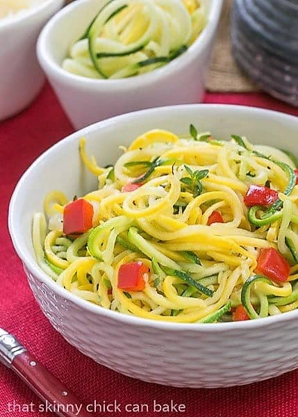 Zucchini Noodles with Parmesan - A light, healthy side dish! Only takes minutes to make! Zucchini Noodles with Parmesan in a white basket weave bowl with a red handle fork.