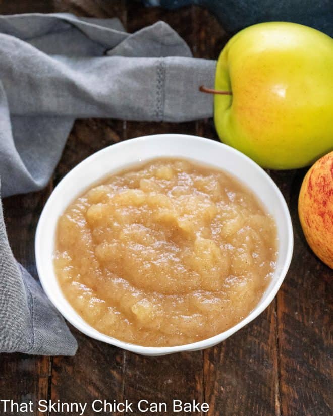 Cinnamon Spiced Applesauce - Classic applesauce recipe that's so easy and delicious! Overhead view of small bowl of apple sauce next to 2 apples.