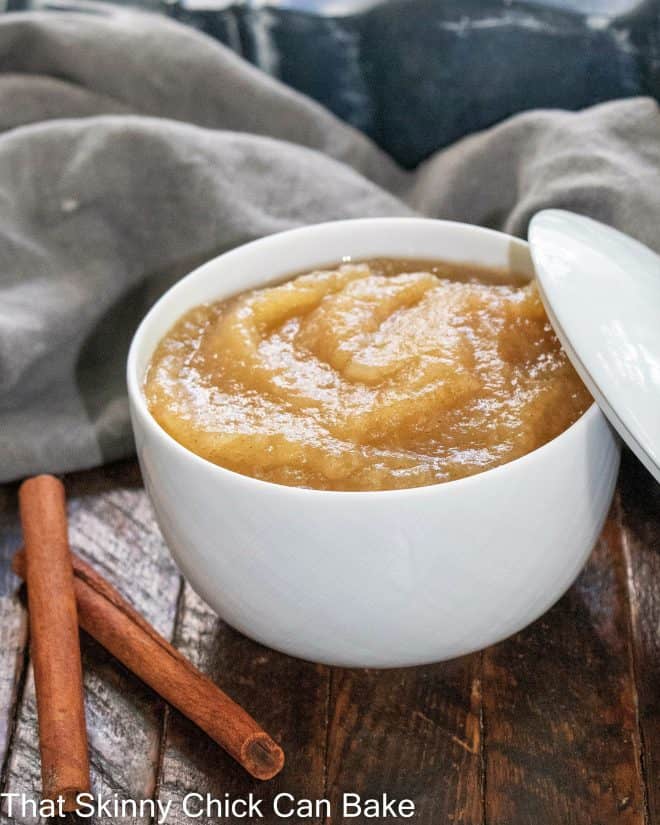 Cinnamon Spiced Applesauce - Classic applesauce recipe that's so easy and delicious! Bowl of homemade cinnamon applesauce next to 2 cinnamon sticks.