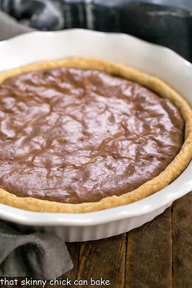 Fudgy Brownie Pie - Rich brownie filling studded with chocolate chips and baked in a flaky pastry shell! Fudgy Brownie Pie in white, fluted ceramic pie plate.
