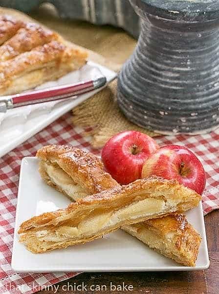 Maple Glazed Apple Tart - Puff pastry, sweetened cream cheese, apples and a maple glaze make for a spectacular breakfast or dessert Maple Glazed Apple Tart slices on a square white ceramic plate.