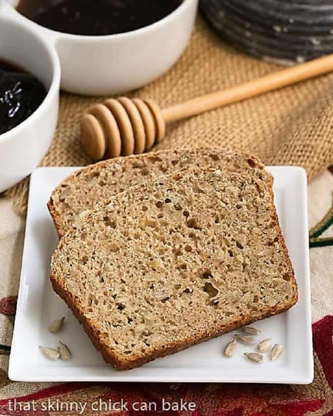 Sunflower Whole Wheat Bread - A whole wheat quick bread with oats, buttermilk and sunflower seeds! Sunflower Whole Wheat Bread slices on a square white plate with jelly.