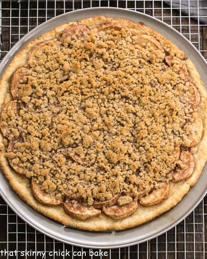 Apple Pie Pizza - A dessert pizza made with a pastry crust, spiced apples, and a crumb topping! An easy apple recipe with the taste of a Dutch Apple Pie! Overhead view of Apple Pie Pizza baked on a pizza pan.