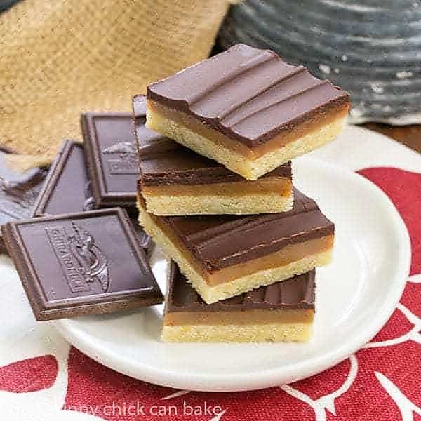 Ganache Topped Caramel Bars - Shortbread crust, caramel filling and creamy ganache topping make for one exquisite bar cookie Ganache Topped Caramel Bars stacked on a round white plate