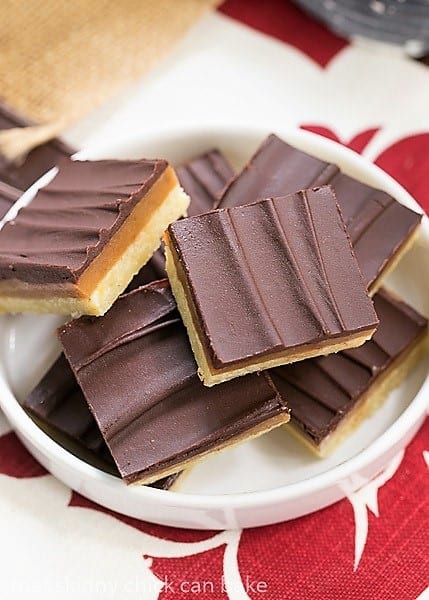 Ganache Topped Caramel Bars - Shortbread crust, caramel filling and creamy ganache topping make for one exquisite bar cookie Ganache Topped Caramel Bars on a rimmed white plate.