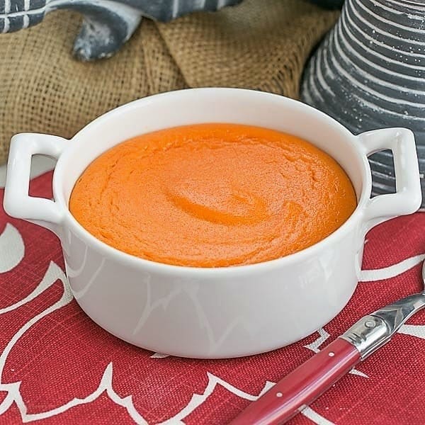 Carrot Souffle - A lovely twist for your vegetable course. Perfect for the holidays! Carrot Puff in a round white baking dish with a red handled spoon.