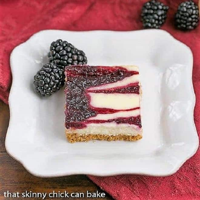 Blackberry Cheesecake Bars - Sublime cheesecake bars with swirls of blackberry jelly Blackberry Cheesecake Bar on a square white plate