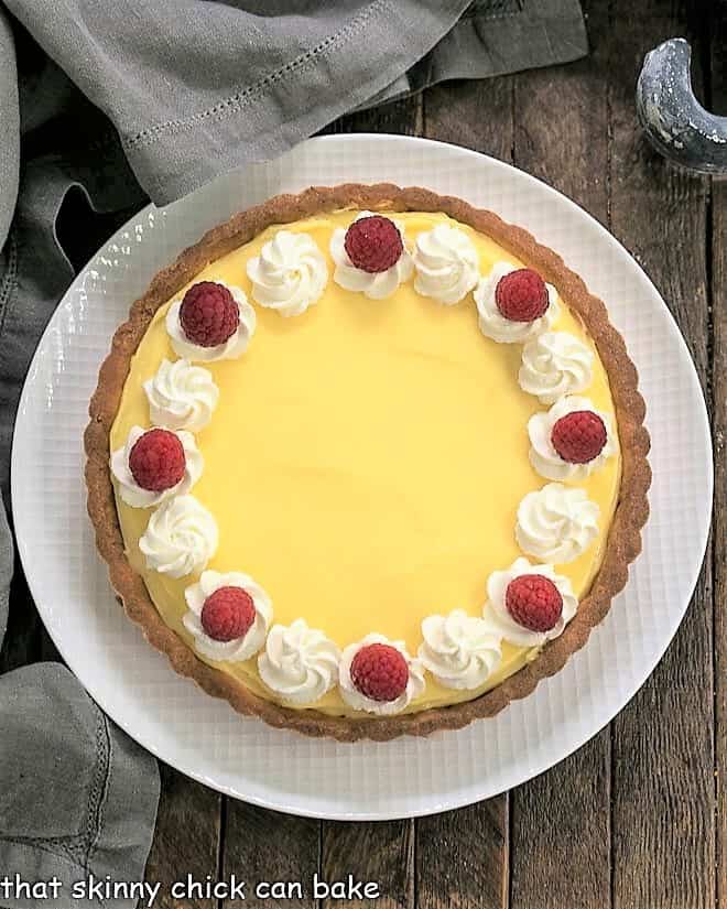 Creamy Lemon Tart - A French citrus tart that will dazzle every lemon lover! The lemon curd filling is exquisite! Overhead view of Creamy Lemon Tart on a white plate.