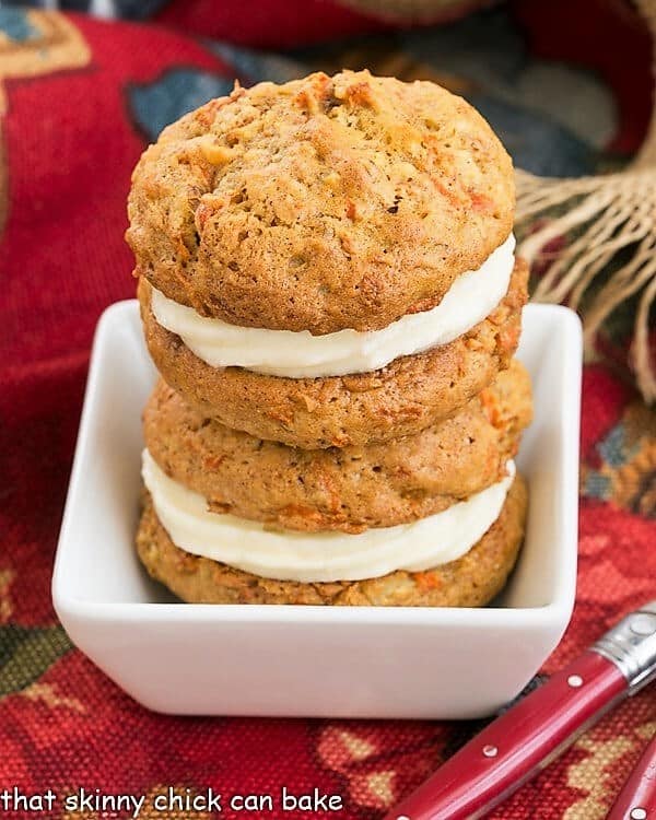 Carrot Cake Whoopie Pies - All the magnificent flavors of a moist carrot cake recipe in these fabulous whoopie pies. 2 Carrot Cake Whoopie Pies stacked in a white bowl.