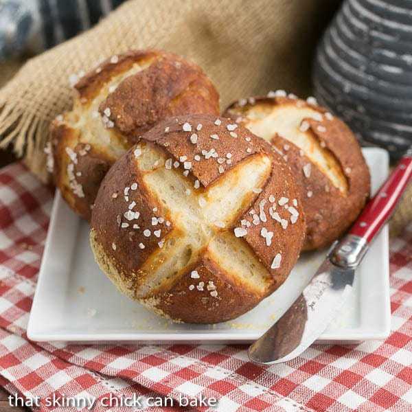 Pretzel Rolls on a square white plate with a red handled knife.