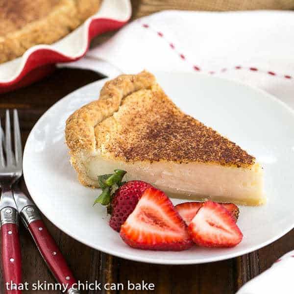 Sugar Cream Pie - A classic dessert in Indiana made with sugar, cream and vanilla! A slice of Hoosier Sugar Cream Pie on a white plate with strawberry slices.