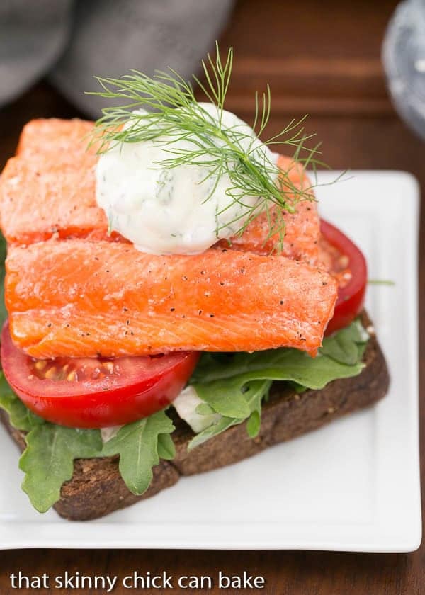 Open-Faced Salmon Sandwiches with Herb Cucumber Relish- This is one heck of a marvelous sandwich!!! Open-Faced Salmon Sandwiches with Herb Cucumber Relish on a square white plate with a dollop of relish and dill sprig to garnish.