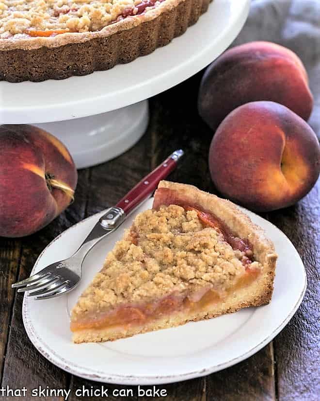 Slice of Streusel Topped Peach Tart on a white dessert plate