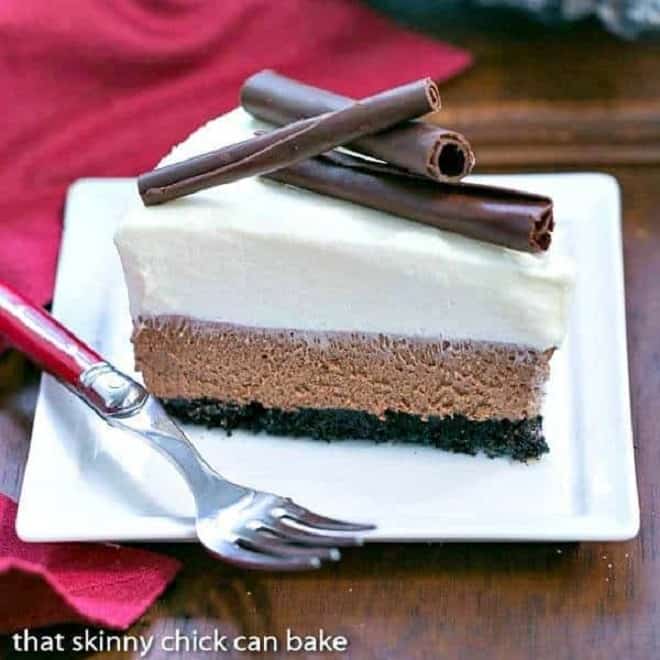 Slice of mousse pie on a square white plate with a red napkin and fork