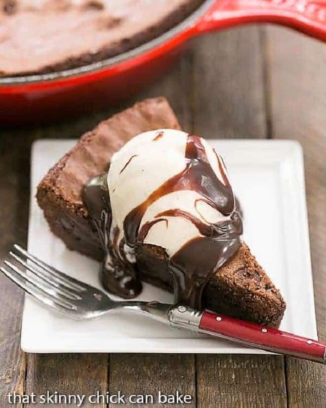 Fudgy Skillet Brownies - One bowl, one pan, one decadent dessert! Fudgy Skillet Brownies slice on a square white plate with a red handled fork.