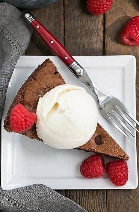 Overhead view of a wedge of skillet brownies on a square white dessert plate.