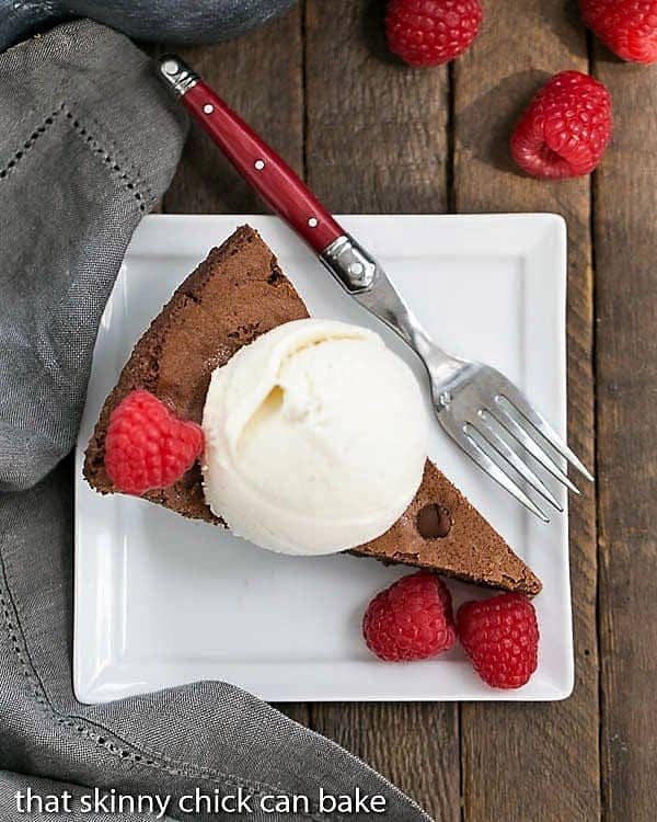 Fudgy Skillet Brownies - One bowl, one pan, one decadent dessert! Slice of a Fudgy Skillet Brownies with ice cream and berries on a square white plate with a fork.