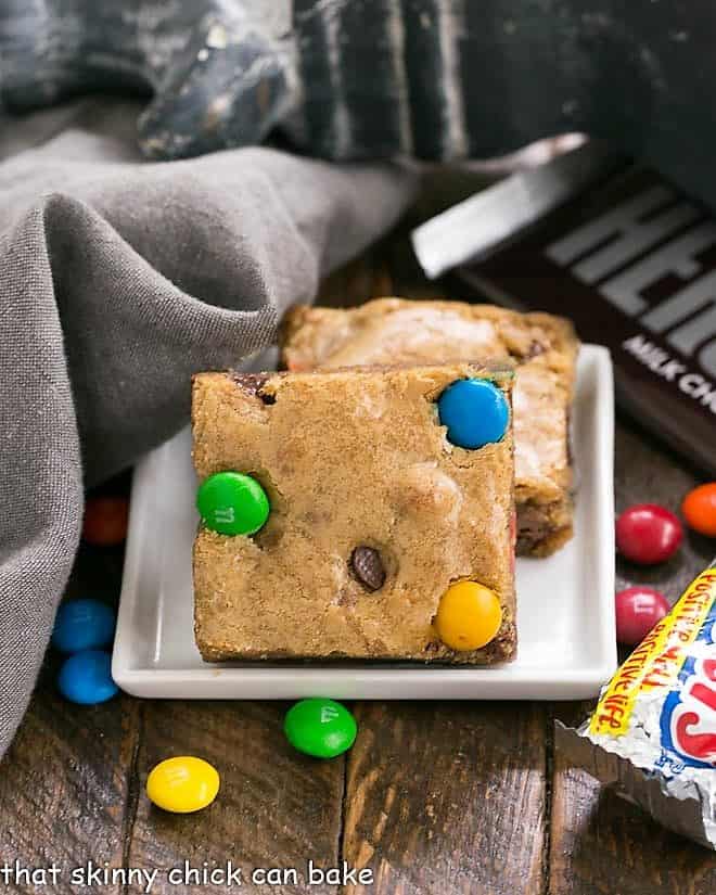 Candy Bar Blondies - The perfect way to use up any leftover candy! 2 Candy Bar Blondies on a square white plate.
