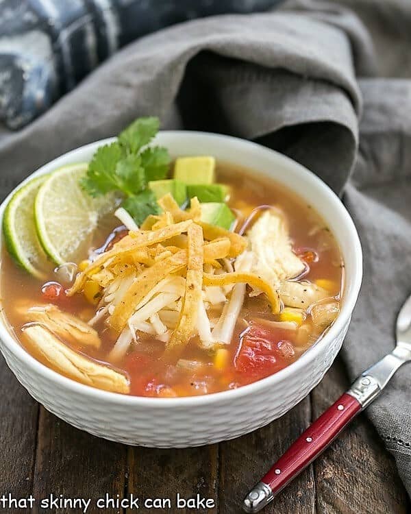 Leftover Turkey Tortilla Soup - A hearty soup that utilizes leftover turkey! Leftover Turkey Tortilla Soup in a white bowl garnished with lime and cilantro sprigs.