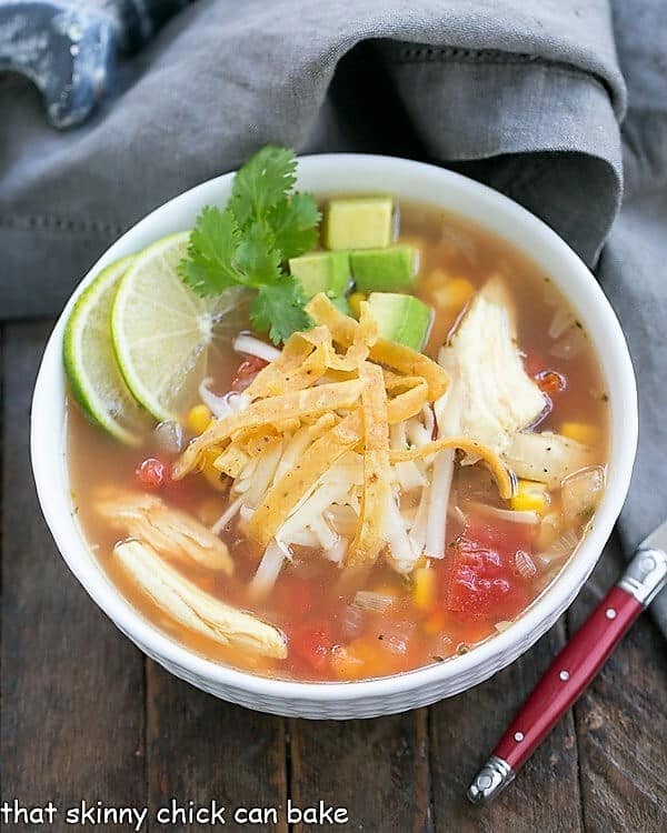 Leftover Turkey Tortilla Soup - A hearty soup that utilizes leftover turkey! Leftover Turkey Tortilla Soup in a white bowl with a red handled spoon.