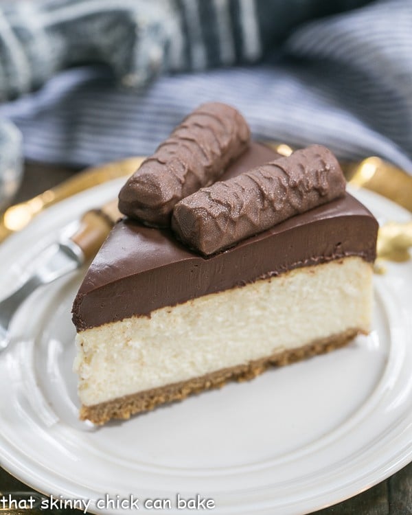 A slice of Twix Cheesecake on a white plate.