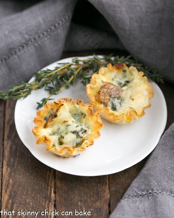 Potato Blue Cheese Tartlets on a round white plate with a sprig of thyme.