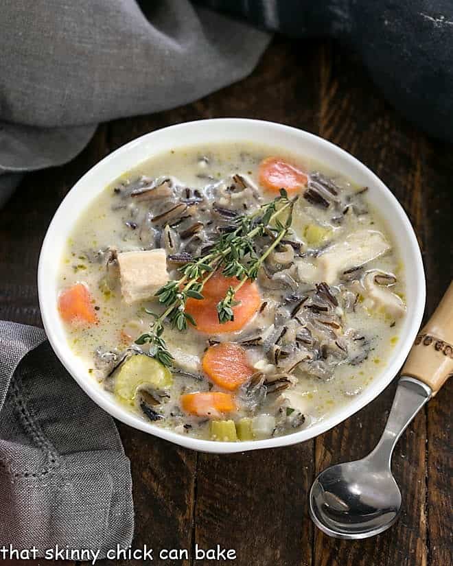 Overhead view of a bowl of wild rice soup with a bamboo handle spoon.