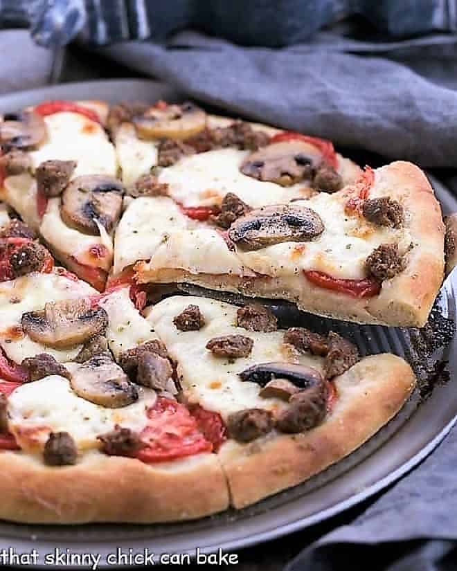 Sausage Mushroom Pizza - Made with a fabulous homemade, yeast dough crust. Perfect for Friday movie night or game day! Sausage Mushroom Pizza with slice being removed from a pizza pan