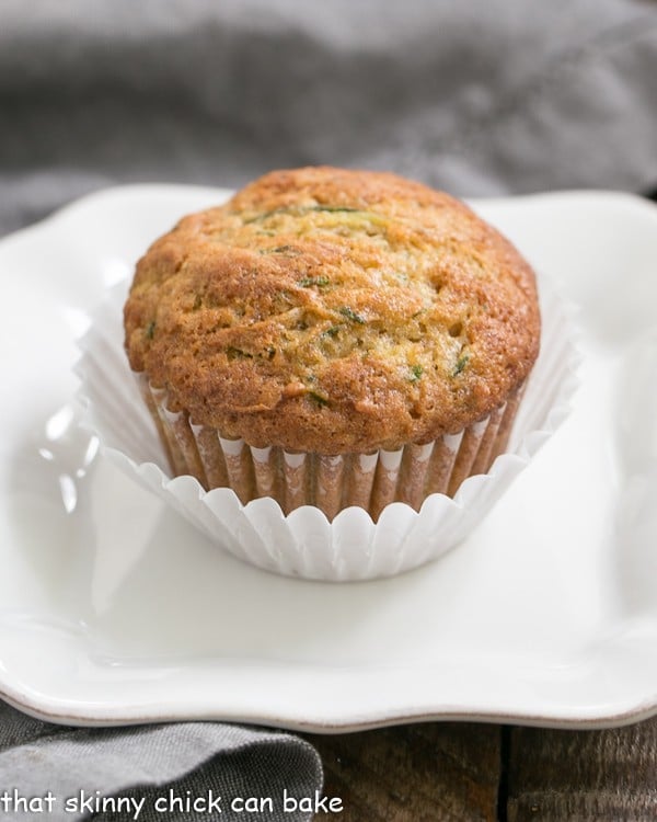 Cinnamon Zucchini Muffins on a white plate in a double white paper muffin wrapper.