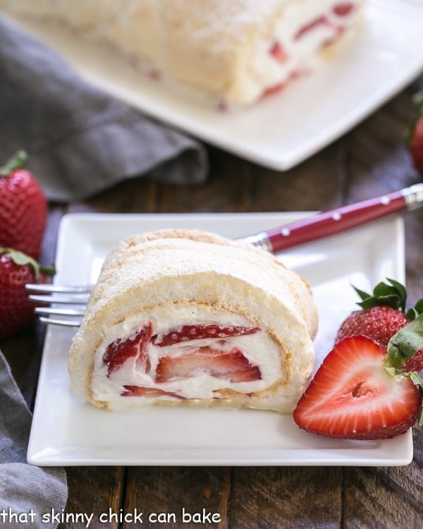 Strawberry Filled Meringue Roulade - A simple baked meringue rolled around strawberries and cream! Strawberry Filled Meringue Roulade slice on a white dessert plate