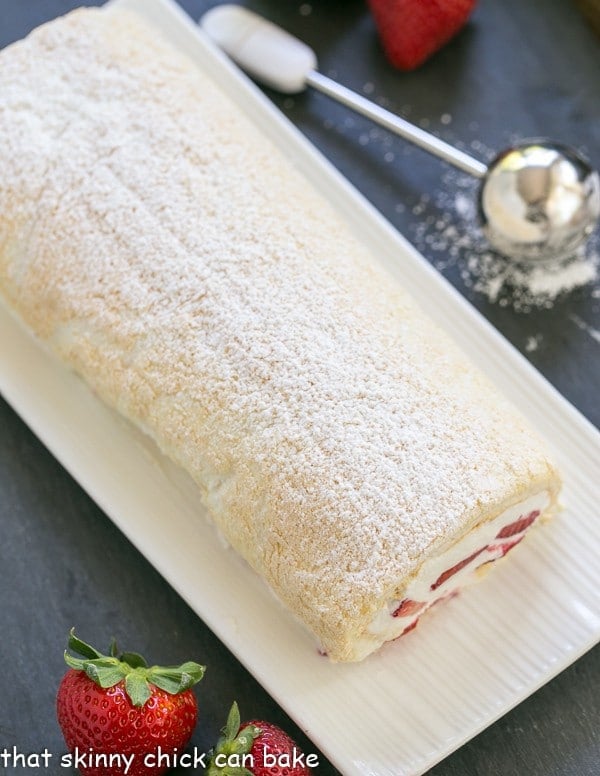 Angel Food Cake Roll - A simple baked meringue rolled around strawberries and cream! Strawberry Filled Meringue Roulade on a white ceramic serving tray