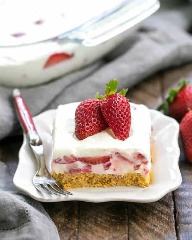 Strawberry Cheesecake Lush Dessert - A dreamy, no-bake treat with a graham cracker crust, berries and cream, plus a No-Cool Whip recipe! Strawberry Cheesecake Lush Dessert on a white dessert plate