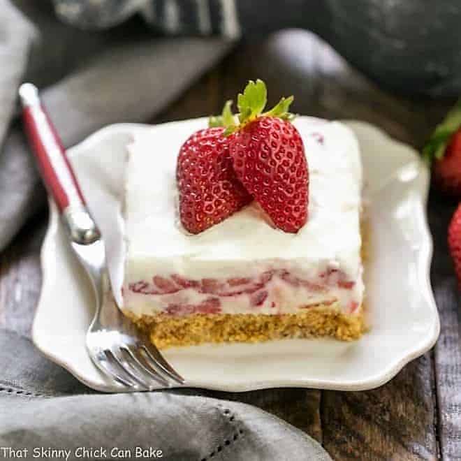 Strawberry Cheesecake Lush Dessert - A dreamy, no-bake treat with a graham cracker crust, berries and cream, and NO Cool Whip! Strawberry Cheesecake Lush Dessert slice on a white dessert plate
