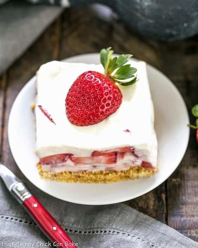Strawberry Cheesecake Lush Dessert - A dreamy, no-bake treat with a graham cracker crust, berries and cream, and NO Cool Whip! Strawberry Cheesecake Lush Dessert slice on a round white plate