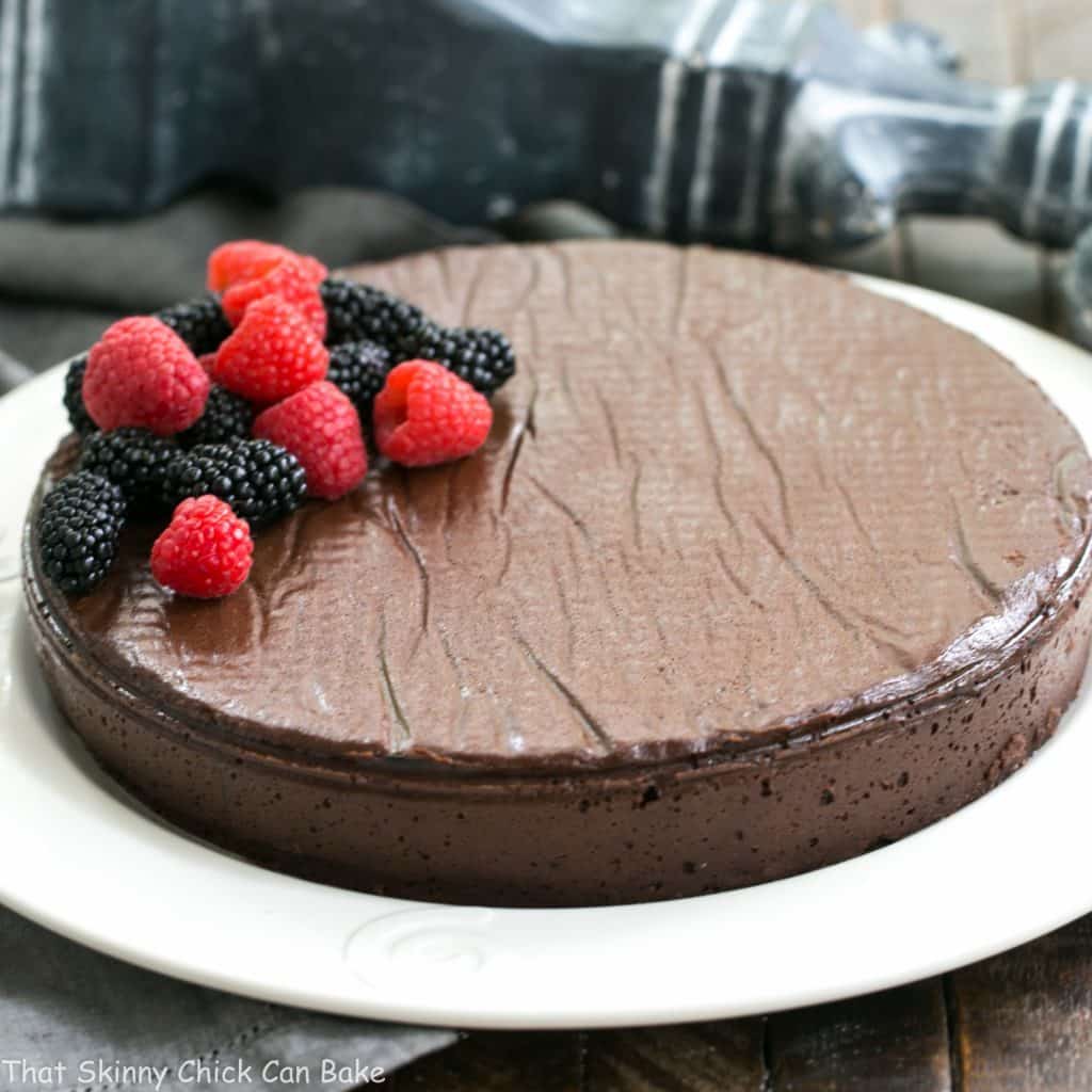 Flourless Cake Chocolate from Princeville Hotel - 5 simple ingredients make for one decadent, outrageously delicious dessert! Flourless Cake Chocolate from Princeville Hotel on a white serving plate garnished with fresh berries.